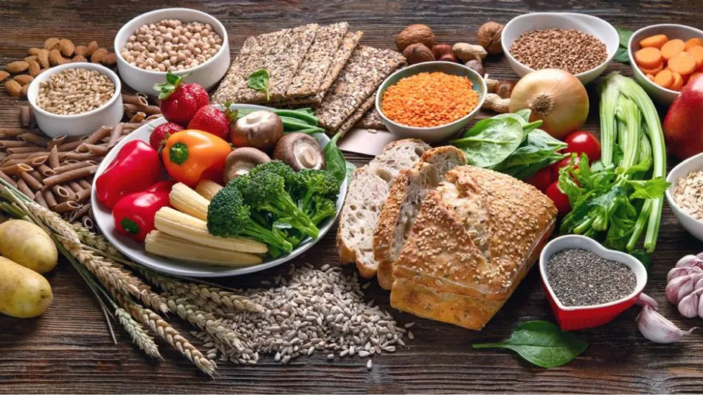 Variété d'aliments riches en fibres tels que les légumes, les grains entiers, les légumineuses et les graines sur une table en bois