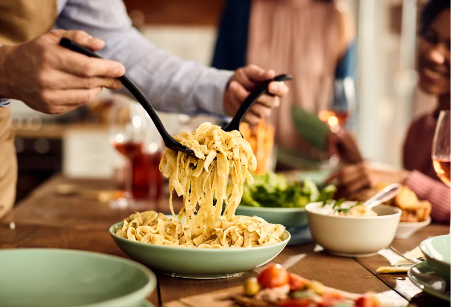 gros plan sur un homme ramassant une portion de fettuccine