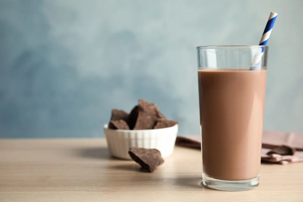 boisson au chocolat sur une table, avec des morceaux de chocolat en arrière-plan