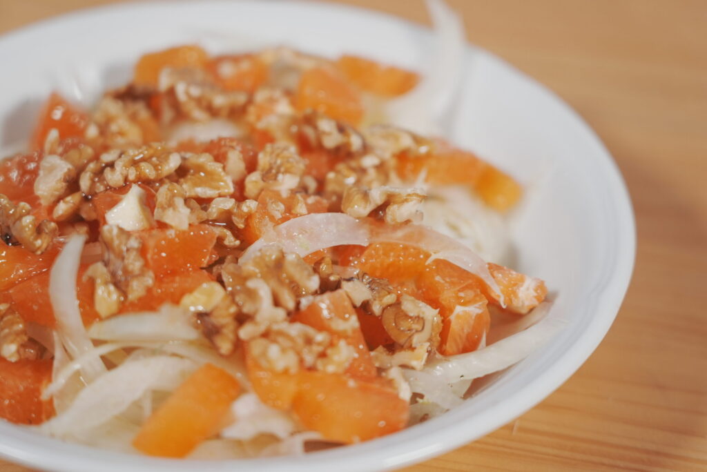 Salade de fenouil et d’orange avec des noix, servie dans une assiette blanche.