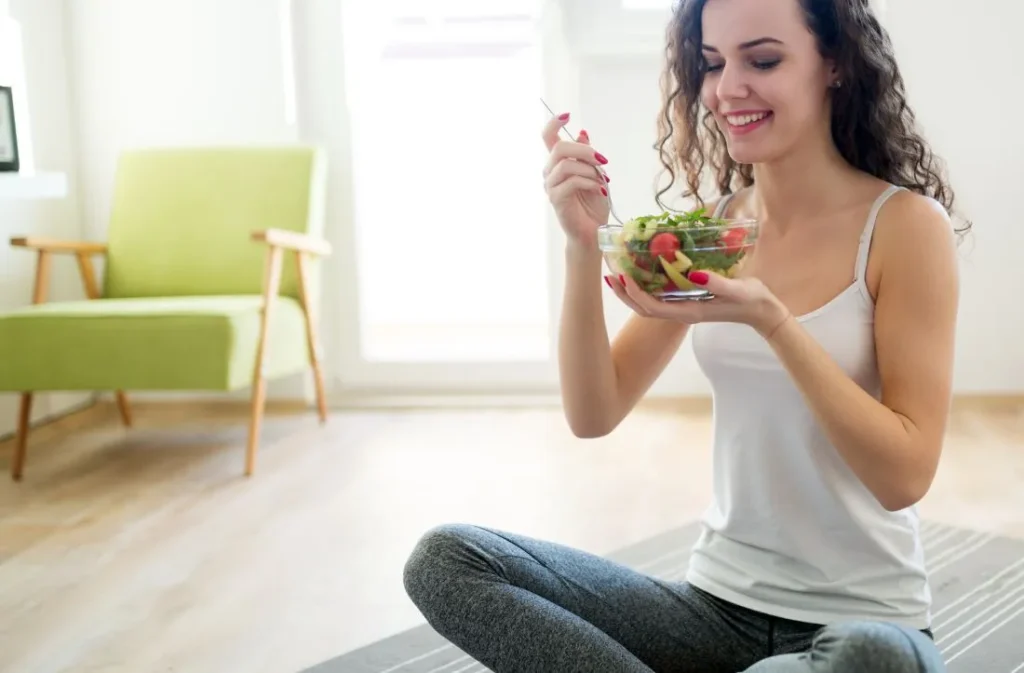 une femme assise par terre en train de manger des légumes